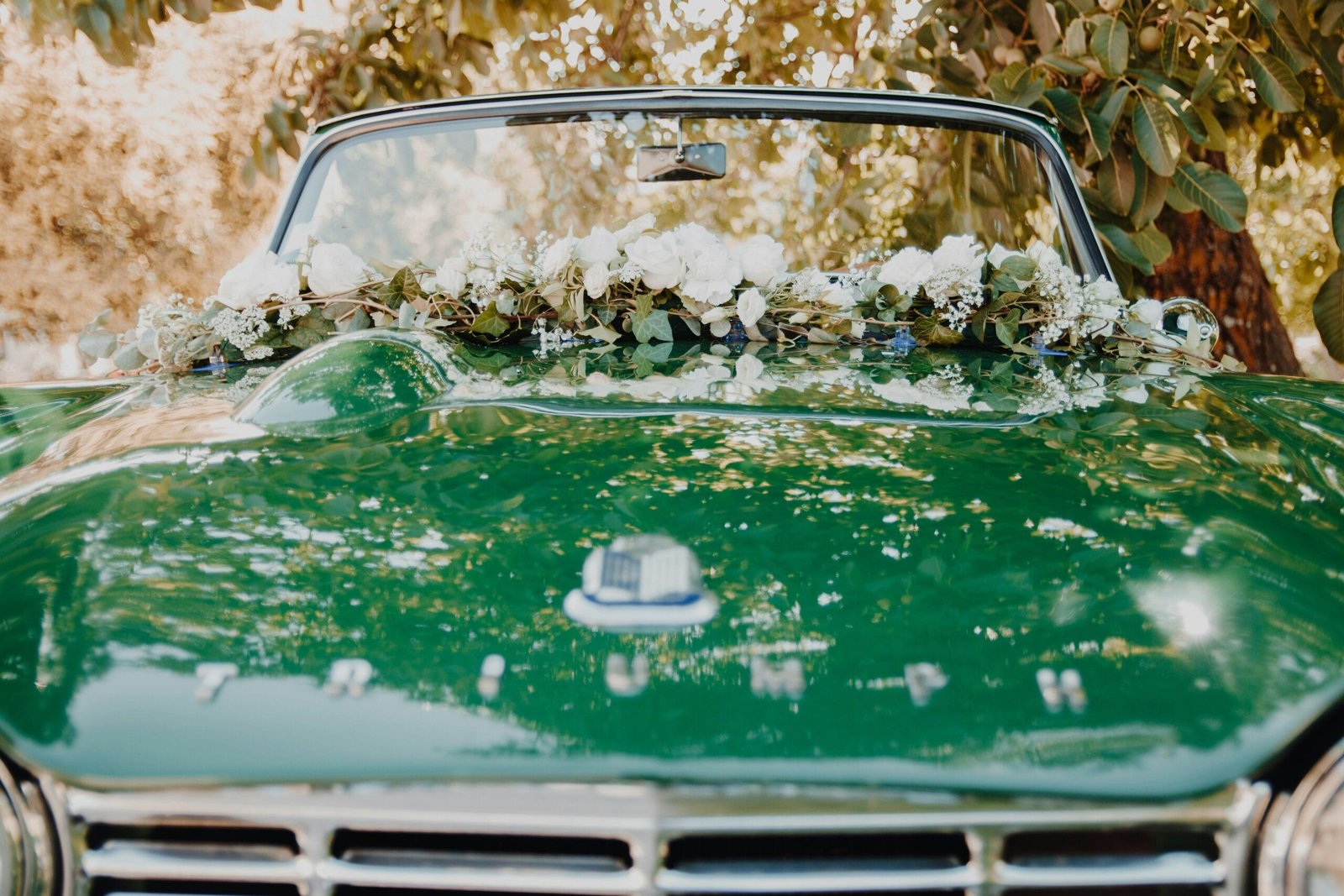 une voiture verte avec un bouquet de fleurs sur le capot
